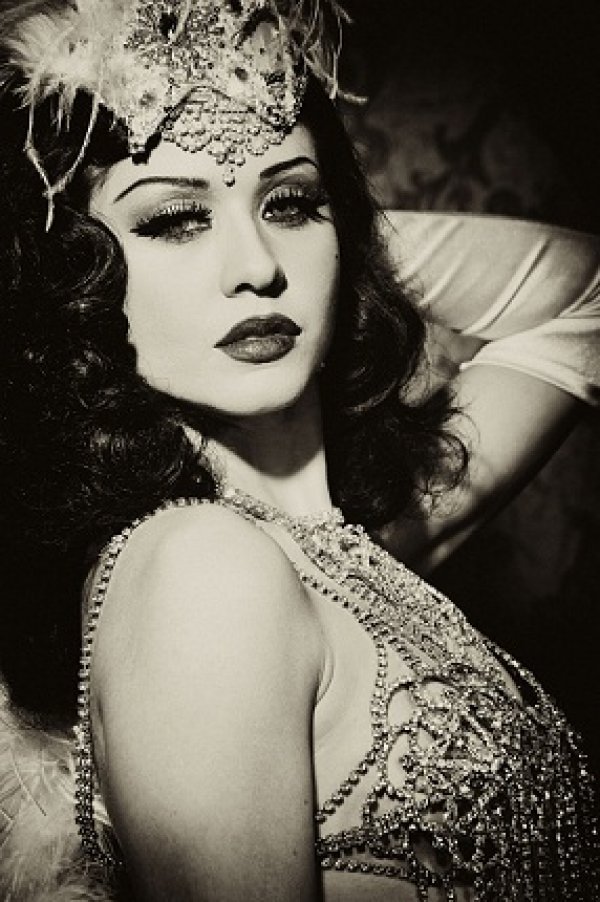 Dolly Lamour (Италия)...Dolly Lamour е една от най-ярките звезди на небосклона на съвременната бурлеска. Магнетичността й е засвидетелствана в рекламни кампании на големи италиански модни дизайнери. Името й, сякаш захарен сироп, е дяволска клопка. Способността й да мимикрира (да се претопява в образи от епохите...) в епохите между 20-те и 50-те години, обличайки роля след роля, зашеметява, замайва неусетно. Така както сладките ликьори разводняват съзнанието. Палитра от женски лица – фаталност, изтънченост, невинна елегантност, Dolly Lamour ще ви отведе в лабиринтите на своя куклен дом.