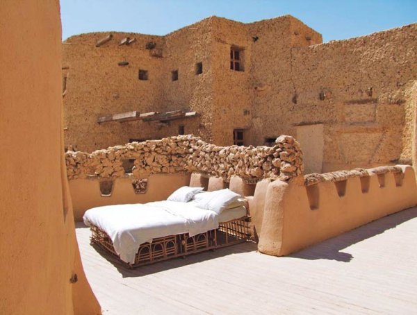 Adrère Amellal Desert EcolodgeОазис Сиуа, ЕгипетТази пустинна резиденция е построена от кал и солни кристали и се намира в основата на свещена, за местните хора, планина. Тук няма никакво електричество, освен малък генератор, захранващ кухнята на хотела, а леглата за спане под звездите се разполагат на покрива или в самата пустиня. Първо се сервира обилна вечеря с кристали и сребро в огромната „бална зала” (низина сред гигантски дюни), след което персоналът, облечен в туники и тюрбани, ви ескортира до пустинната ви стая без фенери или факли. Върви се в пълен мрак сред море от пясък. Така достигате до супер луксозното си легло от палмова дървесина, застлано с изумителни чаршафи от египетски памук, в което потъвате като в облак. Ако заспите твърде бързо обаче, ще изпуснете магията на абсолютната уникална тишина. Пустинните стаи можете да ползвате срещу цена от $800 на нощ.Снимка: Siwa Sustainable Development Initiative