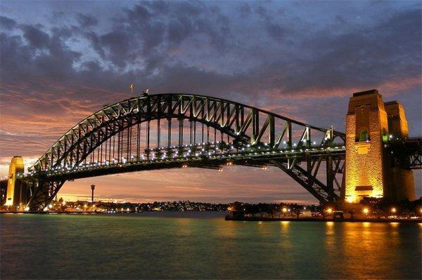Снимка: Sydney Harbour Bridge, АвстралияТова стоманено съоръжение, в най-големия австралийски град, успява да понесе ежедневно железопътно, моторно, вело и пешеходно движение в огромен размер. Драматичната гледка от моста към пристанището и Операта в Сидни се е превърнала в снимка-икона за града. Мостът е проектиран и построен от английската фирма „Дорман Лонг и Ко" и е открит през 1932 година.