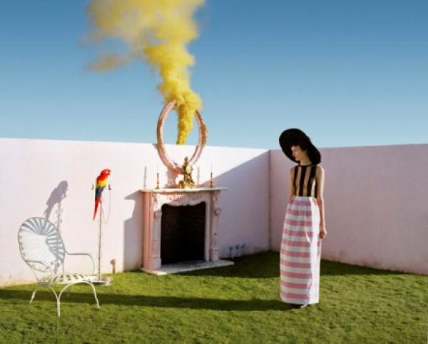 Кирси Пироен на ивици с папагала и жълт димМода: Jil Sander, снимки: Sennowe Park, Norfolk, 2010„Трябваше да снимаме на горещо място, така че вместо в Мексико, ние отидохме в Норфолк. Просто така се случи, уцелихме невероятно време с тропическо синьо небе. Беше септември. Повторно пресъздадохме градина върху покрива на Льо Корбюзие, предназначена за апартамент в Париж през 1920 година”.Снимка: fashion.telegraph.co.uk